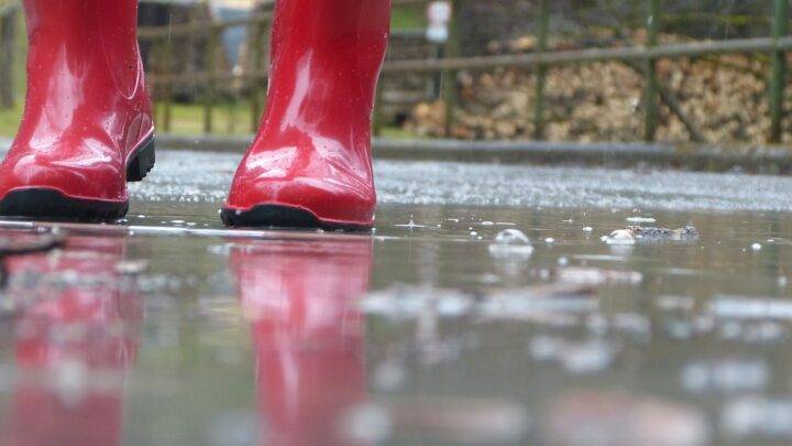 Rote Gummistiefel in einer Pfütze