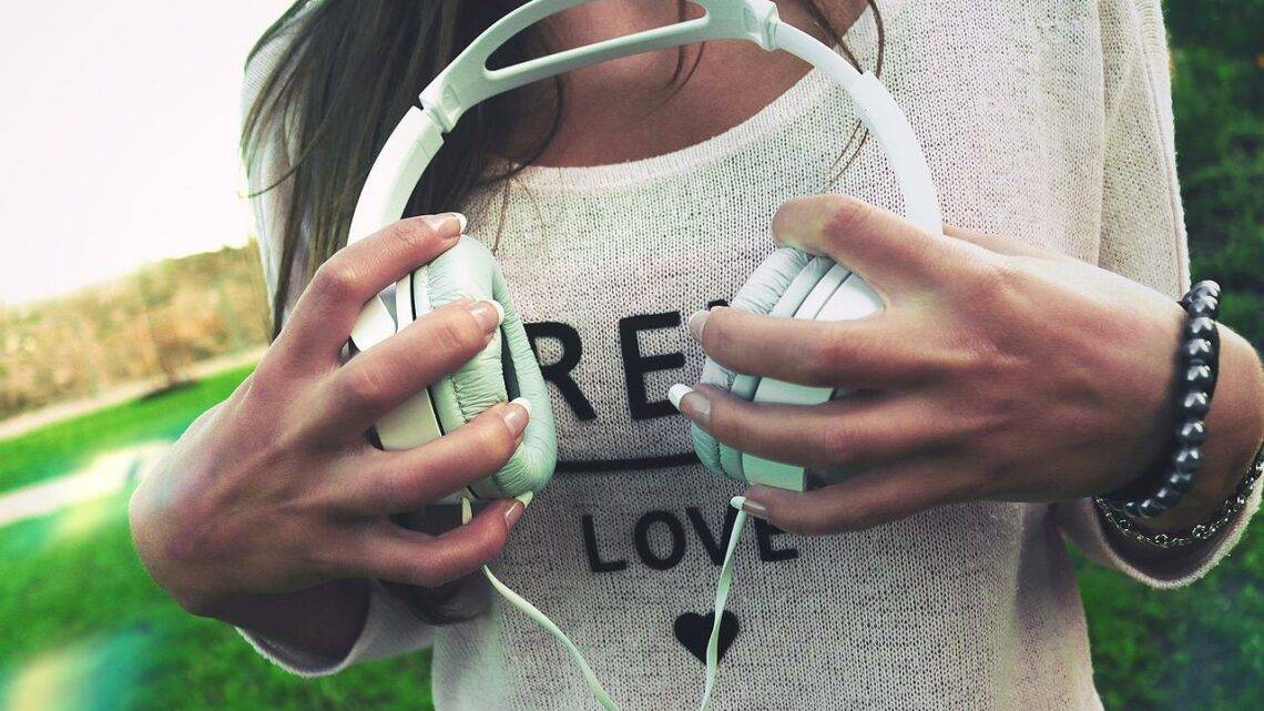 Frau hält weiße Over-Ear Kopfhörer in der Hand