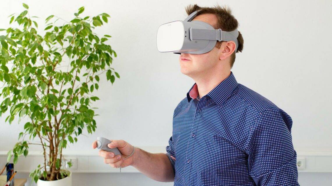 Mann mit VR Brille und Controller im Wohnzimmer